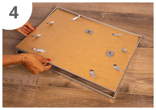 Insere cuidadosamente o puzzle, juntamente com o vidro e o fundo, na moldura.